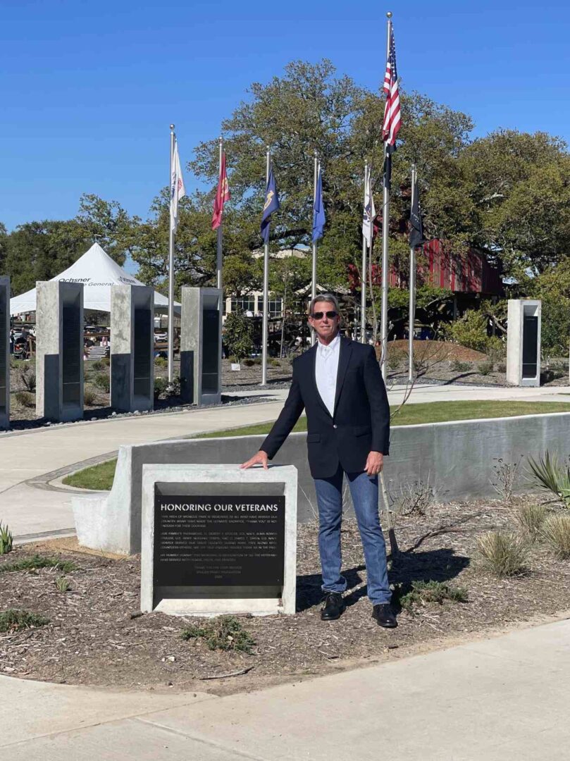 A Man in a Black Color Suit Beside a Memory Stone